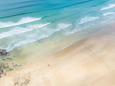 A beach with waves and surfers at Windyhill in Polzeath