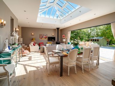 A dining area with a table and chairs next to a living area with sofas under a skylight at Trevanion in Rock