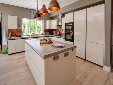 A kitchen with a large island counter under three hanging pendant lights at Trevanion in Rock