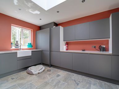 A kitchen with grey cabinets orange walls a window a dog bed and a kettle at Trevanion in Rock