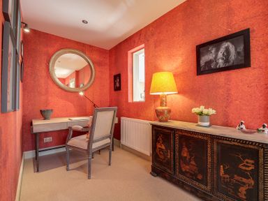 A small room with a desk and chair alongside a decorated cabinet with a lamp and flowers at Trevanion in Rock