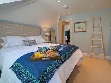 A bedroom with a bed breakfast tray ladder and a painting on the wall at Trevanion in Rock