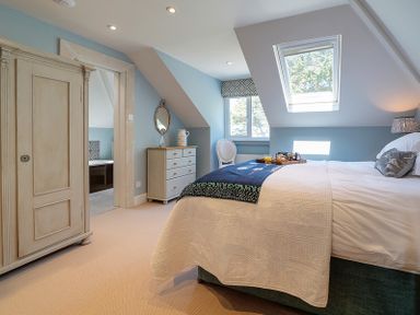 A bedroom with a bed a dresser a wardrobe and a chair under skylight and window at Trevanion in Rock