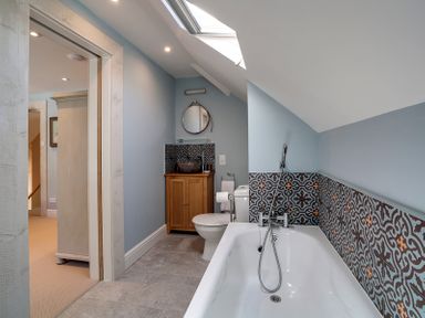 A bathroom with a bathtub toilet sink and patterned tiles at Trevanion in Rock