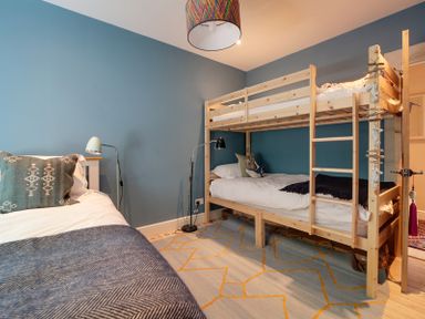 A bedroom with a bunk bed and a single bed against blue walls at Trevanion in Rock