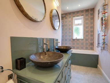 A bathroom with two vessel sinks on a green vanity and a bathtub with patterned tile at Trevanion in Rock
