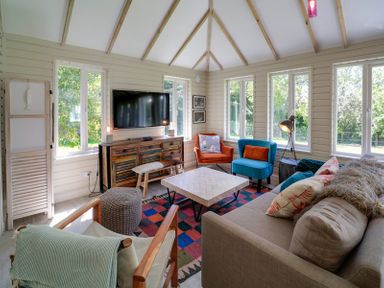 A living room with colorful chairs a wooden cabinet and a television at Trevanion in Rock