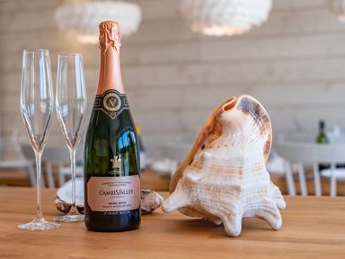A bottle of sparkling wine with two champagne glasses and a large seashell on a wooden table at Seastar in Rock