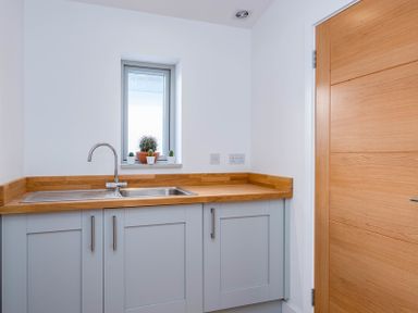 A kitchen corner with a wooden countertop grey cabinets a stainless steel sink and small plants on a windowsill at Seastar in Rock