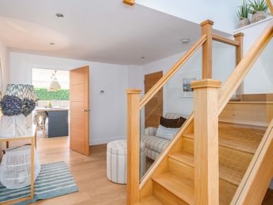 A hallway with wooden stairs a small sofa and a wooden door leading to a kitchen at Seastar in Rock