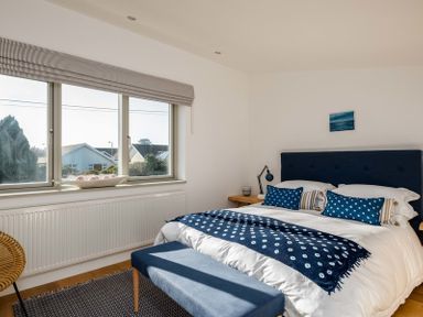 A bedroom with a bed blue and white bedding a blue bench at the foot of the bed by a window at Seastar Rock