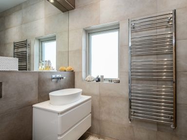 A bathroom with a white sink on a cabinet a metal towel rack and a window at Seastar in Rock