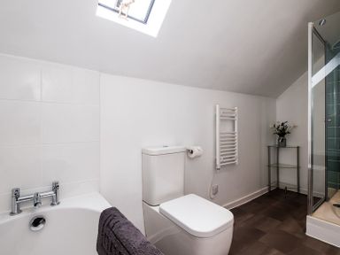 A bathroom with a bathtub toilet towel rack and glass shower at Pinewood 14 in Polzeath