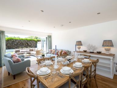 A dining area with a wooden table set for eight and a living area with sofas and armchairs at Artemis in Rock