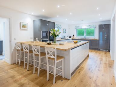 A kitchen with a wooden floor and island with bar stools and cabinets at Artemis in Rock