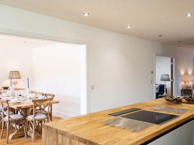 A kitchen with a wooden island countertop and an induction cooktop next to a dining area with a wooden table and chairs at Artemis in Rock