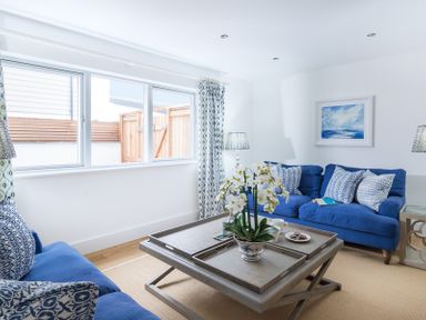 A living room with blue sofas a wooden coffee table and a window with patterned curtains at Artemis in Rock