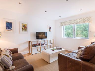 A living room with two brown leather sofas a white table a TV on a shelving unit and a window at Artemis Rock