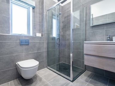A bathroom with a wall-mounted toilet a glass shower enclosure and a vanity with a mirror at Artemis Rock