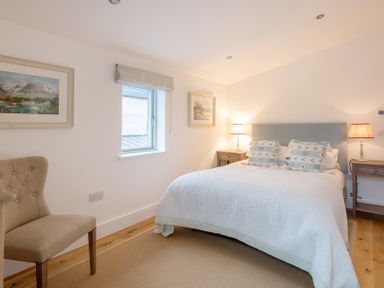A bedroom with a bed chair bedside tables lamps and framed pictures at Artemis in Rock