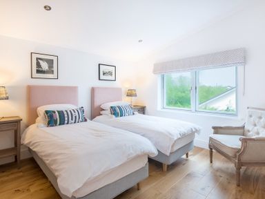 A bedroom with two single beds bedside tables window and an armchair at Artemis in Rock