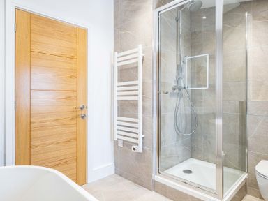 A bathroom with a glass shower enclosure wooden door and a heated towel rail at Artemis Rock