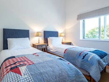 A bedroom with two single beds with patchwork quilts and bedside tables with lamps at Artemis in Rock