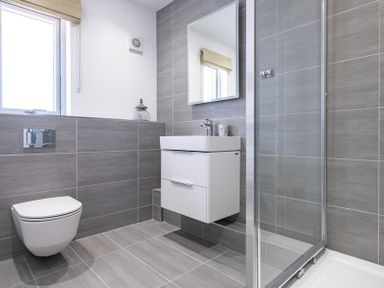 A bathroom with a wall-mounted toilet a floating sink with a mirror and a glass shower enclosure at Artemis in Rock