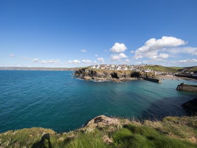 A coastal village with houses on cliffs next to the sea and a harbor with boats at Kipper Cottage in Port Isaac