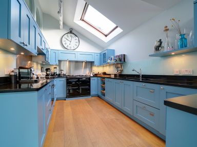 A kitchen with blue cabinets wooden floor a black stove and a skylight at Camel Point in Rock