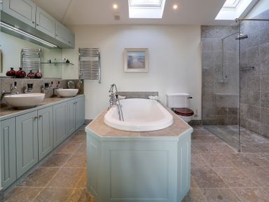 A bathroom with a bathtub shower toilet double sinks and cabinets at Camel Point in Rock