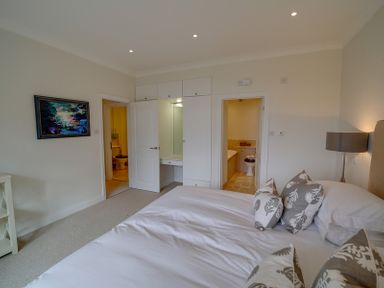 A bedroom with a bed pillows lamp and two open doors showing bathrooms at Camel Point in Rock