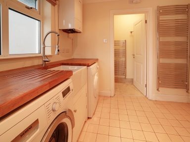 A laundry room with washing machines a sink a wooden countertop and a door leading to another room at Camel Point in Rock