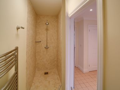 A tiled walk-in shower with metal shower fixtures next to an open door showing a tiled floor at Camel Point in Rock