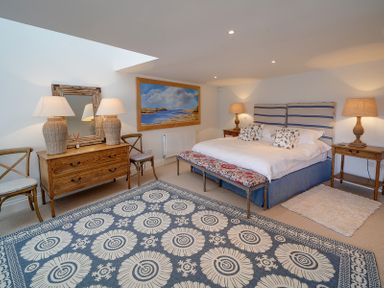 A bedroom with a bed a rug two bedside tables with lamps a chest of drawers with two lamps and two chairs at Camel Point in Rock