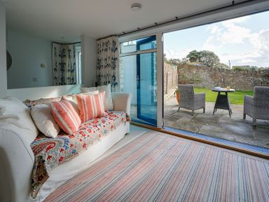 A living room with a sofa with patterned covers and cushions next to sliding glass doors opening to a patio with two chairs and a small table at Camel Point in Rock