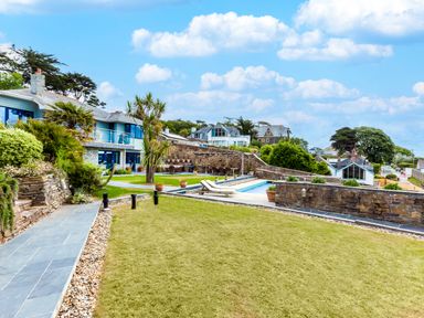 A garden with palm trees a stone pathway and a swimming pool at Camel Point in Rock