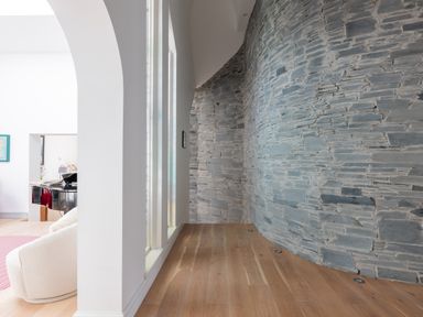 A curved stone wall with wooden floor and white archway leading to a living area at Landers Field in Rock
