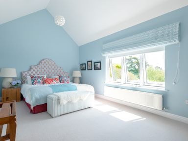 A bedroom with a bed with patterned headboard and blue walls at Landers Field in Rock