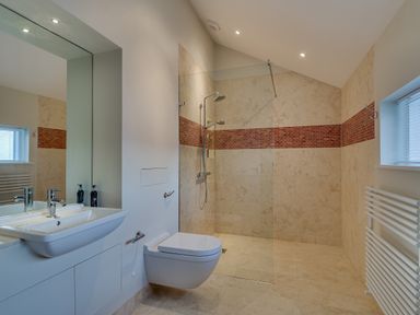 A bathroom with a wall-mounted sink and toilet a walk-in shower with glass divider and tiled walls at Landers Field in Rock