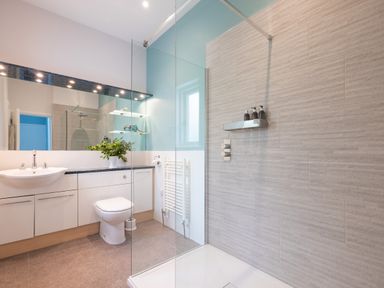 A bathroom with a shower area glass partition toilet sink countertop cabinet mirror and shelves at Landers Field in Rock
