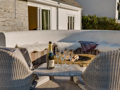 A patio with two wicker chairs a bottle of prosecco and four glasses near a fire pit at Landers Field in Rock