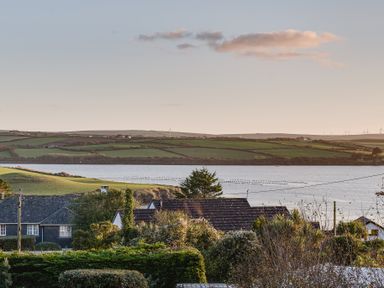 A view of rooftops trees a body of water and green fields with wind turbines in the distance at Landers Field Rock