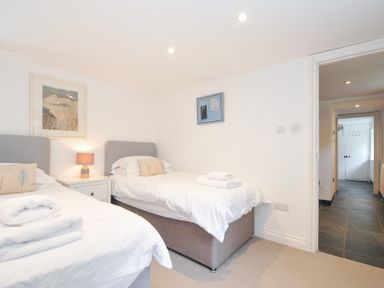 A bedroom with twin beds and a painting at Orchard Cottage in Polzeath