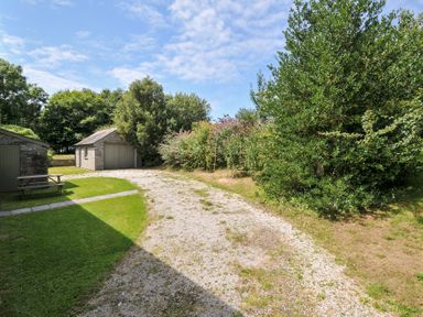 A garden with a gravel path and shed at Orchard Cottage in Polzeath
