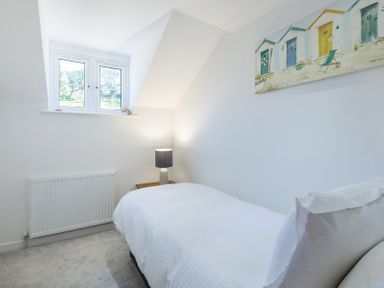 A small bedroom with a single bed a bedside table with a lamp a radiator and a window at Stop Tide in Port Isaac