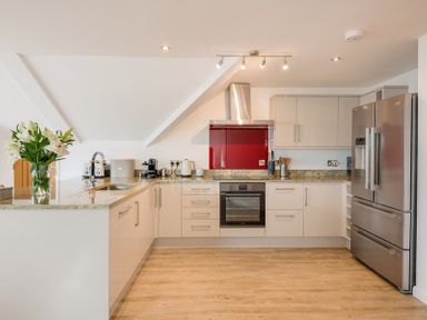 A kitchen with beige cabinets stainless steel appliances a red backsplash and wooden floor at Upper Deck Rock