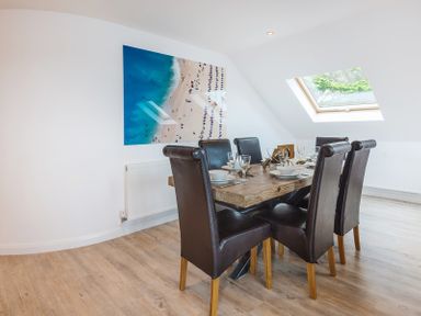 A dining room with a wooden table set for six and dark chairs under a skylight at Upper Deck in Rock