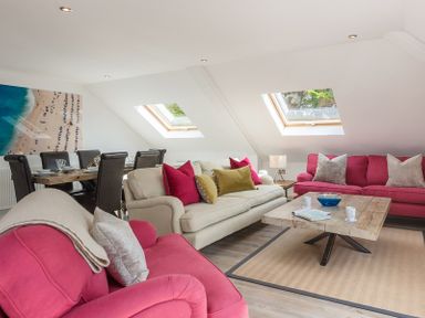 A living room with red and beige sofas a wooden coffee table and a dining table with chairs at Upper Deck in Rock