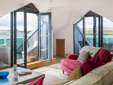 A living room with glass doors opening to a balcony with chairs and a view of fields at Upper Deck in Rock